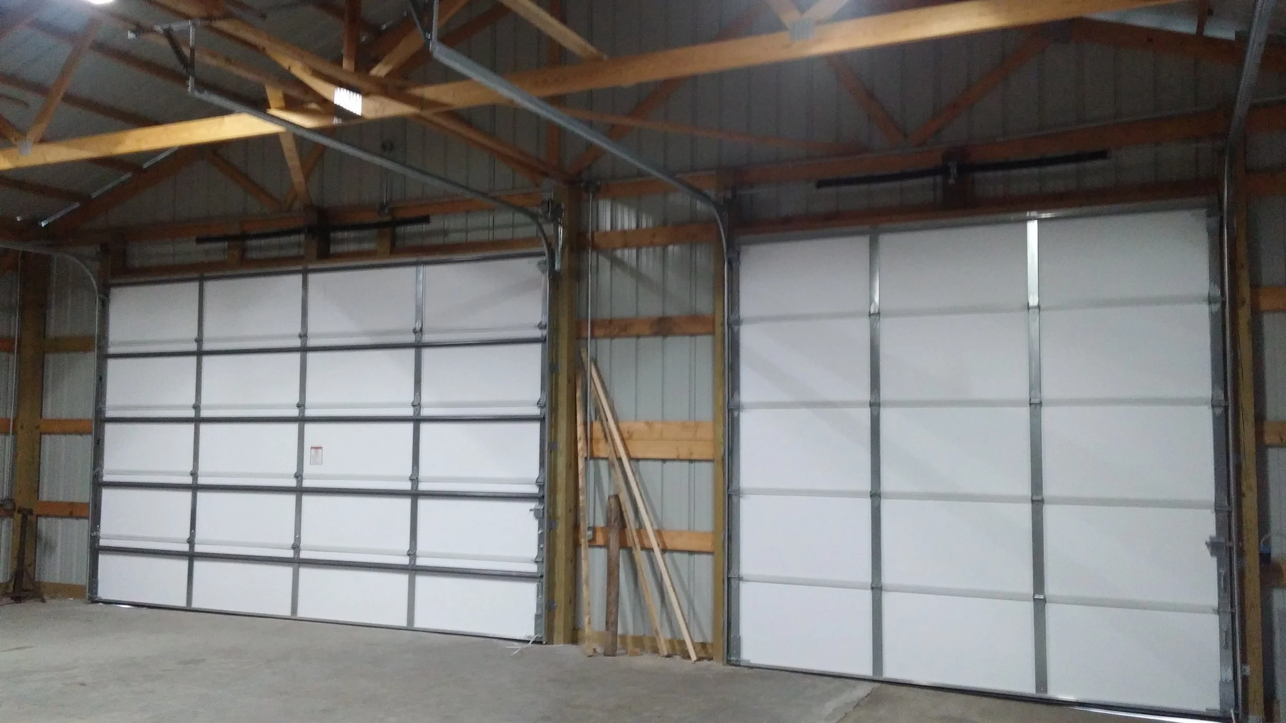 Interior view of two oversized commercial sectional doors mounted on wood-framed openings
