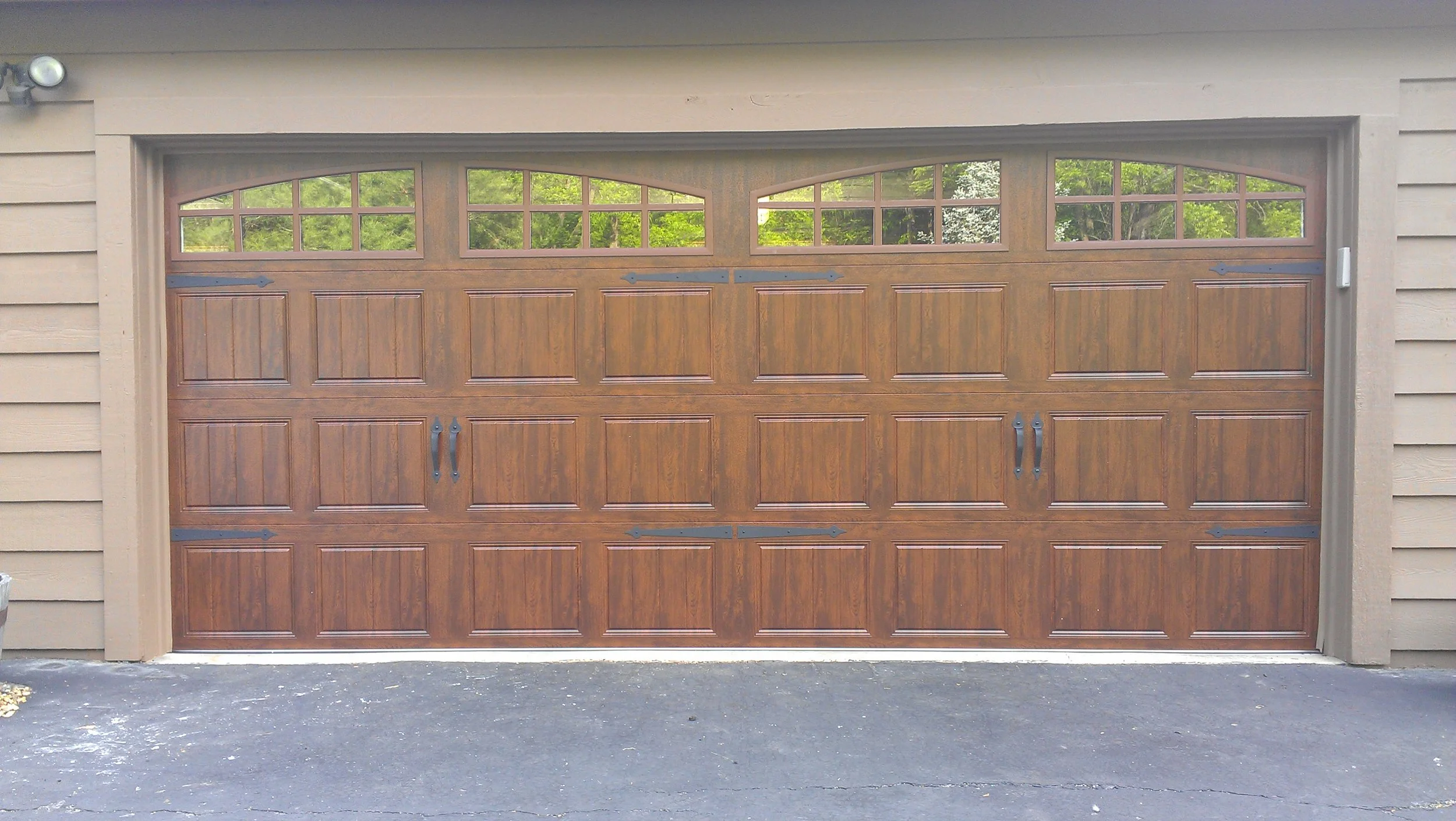 Two-bay residential garage with dark wood-grain carriage doors