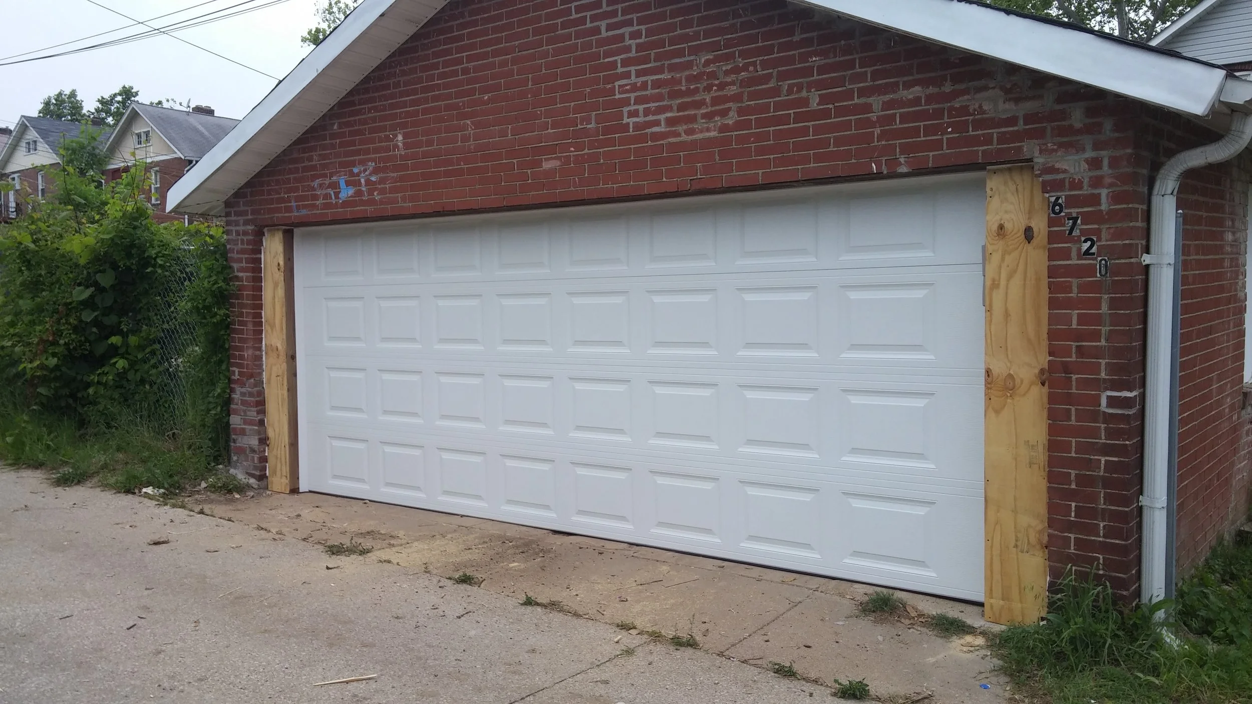 Finished brick garage with the new white raised-panel sectional door installed