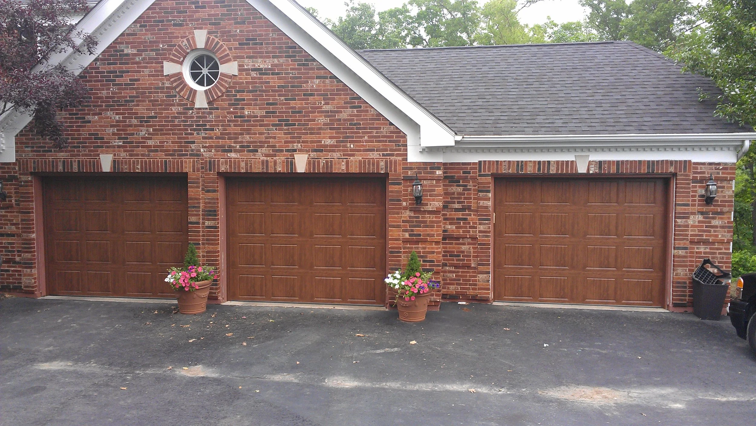 Three-bay brick home with wood-grain residential garage doors