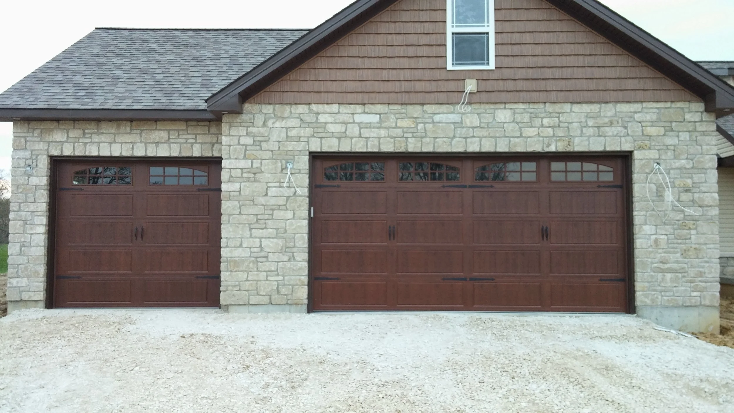 Stone-faced home with two wood-grain carriage-style garage doors