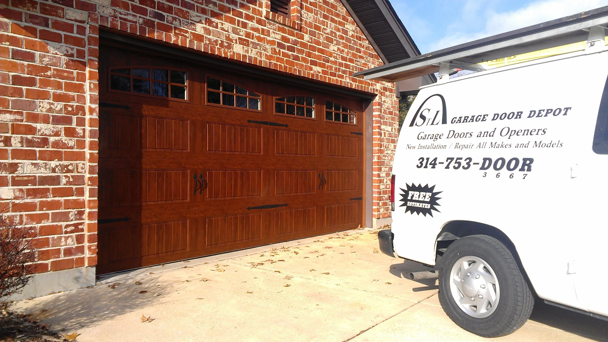 StL Garage Door Depot service truck next to a wood-grain residential garage door on a brick home